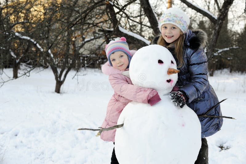 Hermanas con el muñeco de nieve fotos de archivo libres de regalías Hermanas con el muñeco de nieve fotos de archivo libres de regalías