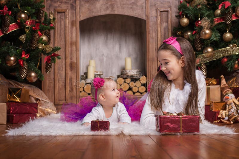 Hermanas lindas que mienten cerca de los árboles de navidad fotografía de archivo Hermanas lindas que mienten cerca de los árboles de navidad fotografía de archivo