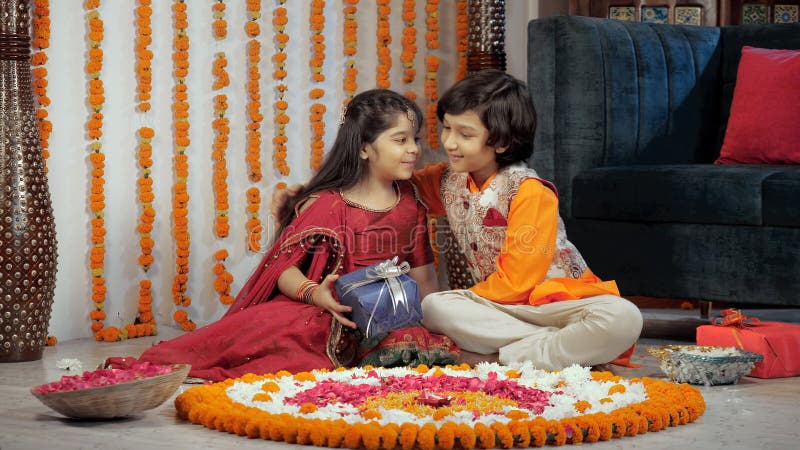 Hermano con ropa tradicional dando un regalo colorido a su linda hermanita en diwali almacen de video