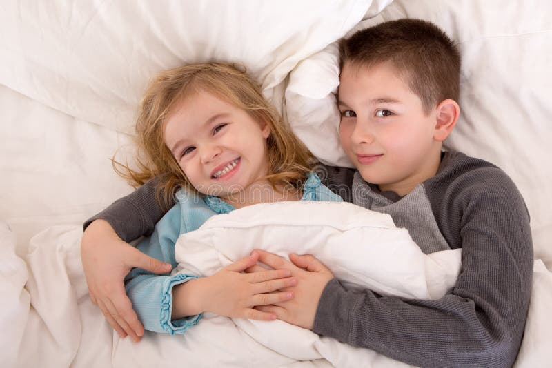 Hermano joven y hermana dañosos en cama imágenes de archivo libres de regalías Hermano joven y hermana dañosos en cama imágenes de archivo libres de regalías