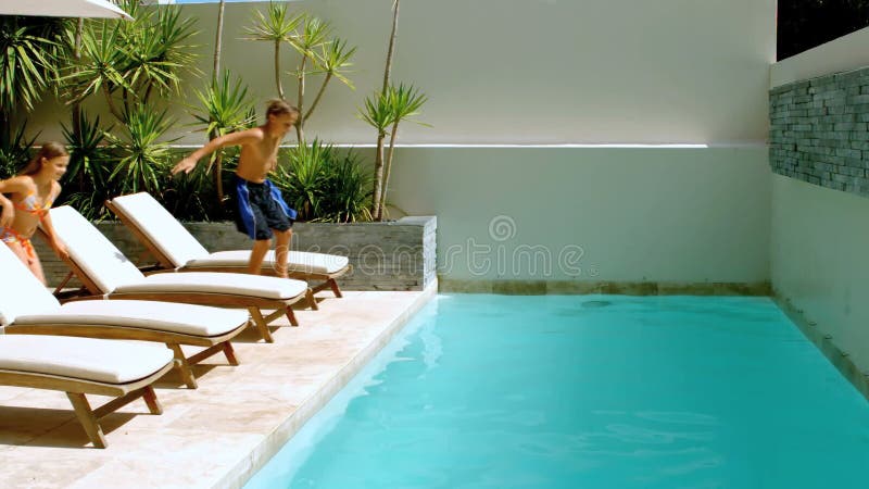 Hermanos felices que se zambullen en la piscina almacen de metraje de vídeo