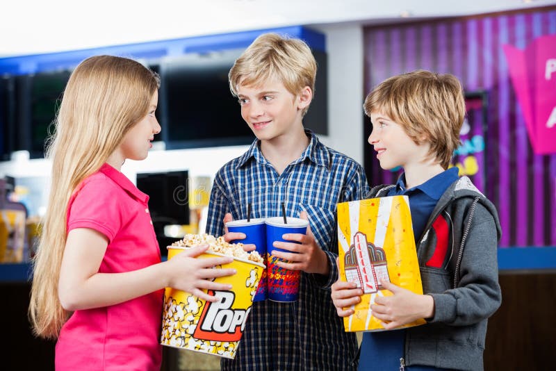 Hermanos que hablan mientras que sostiene los bocados en el cine foto de archivo Hermanos que hablan mientras que sostiene los bocados en el cine foto de archivo