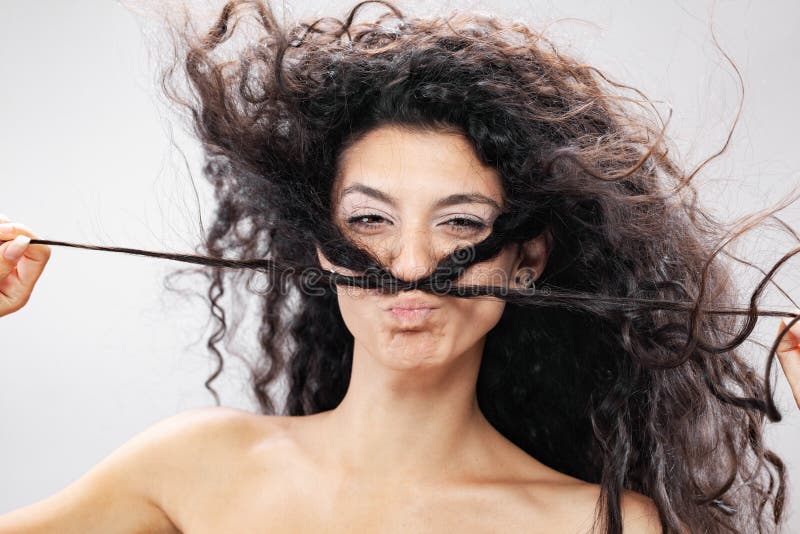 Hermosa chica morena con el pelo largo rizado en el aire retrato de estudio. expresión de cara torpe divertido fotos de archivo