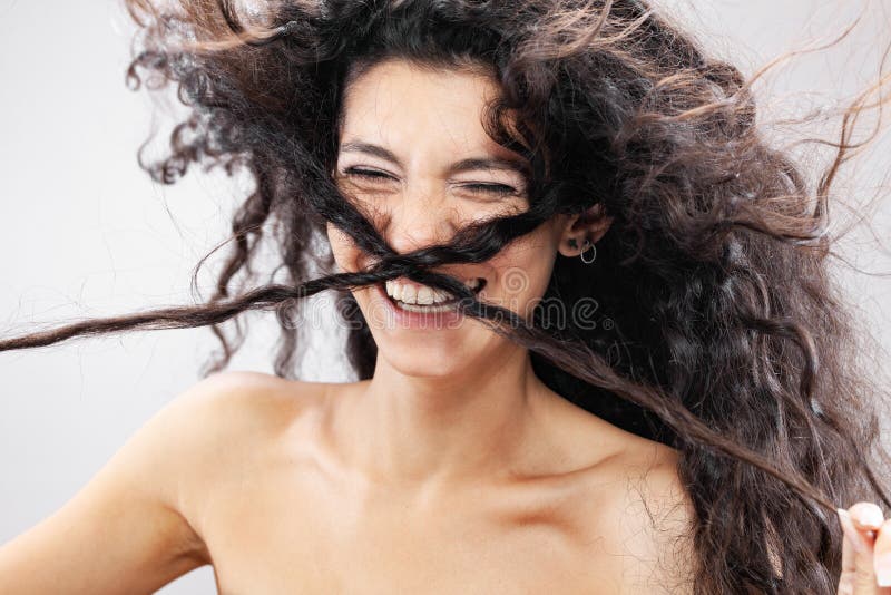 Hermosa morena con pelo largo y rizado en el retrato de estudio de aire. expresión de cara divertida y torpe imagenes de archivo