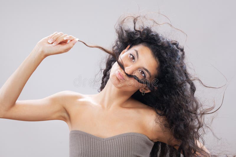 Hermosa morena con pelo largo y rizado en el retrato de estudio de aire. expresión de cara divertida y torpe fotos de archivo libres de regalías