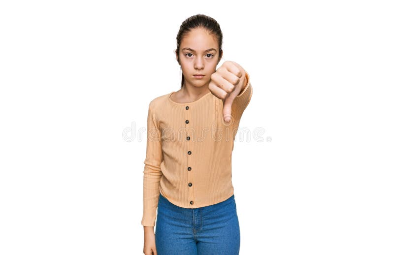 Hermosa morena pequeña niña con suéter casual que se ve infeliz y enojada mostrando rechazo y negativo con el pulgar hacia abajo imagen de archivo