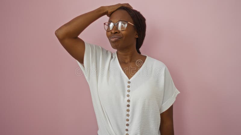 Hermosa mujer afroamericana posando en camisa blanca contra un fondo rosado aislado con una expresión segura foto de archivo libre de regalías