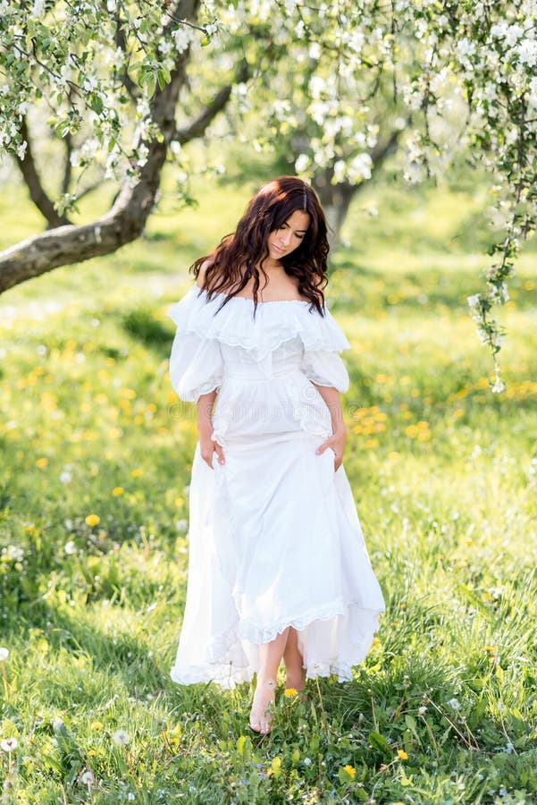Hermosa Mujer En Un Vestido Blanco Largo En Un Jardín De Primavera. Caminar Por El Jardín En Flor de archivo - Imagen de disfrute, exterior: 217764491