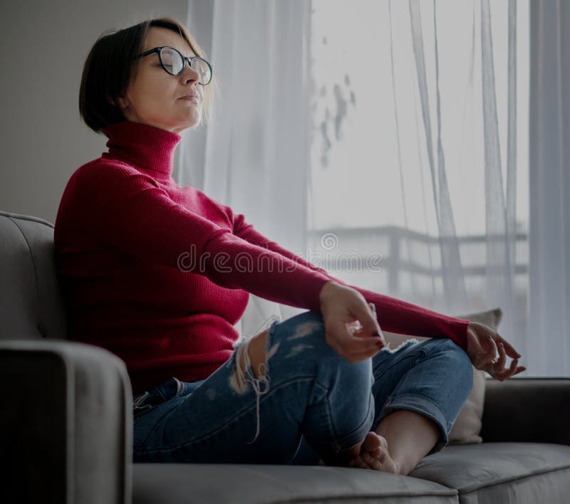 Hermosa Mujer Madura En Gafas Sentada En Casa En El Sofá Meditando En La  Posición De Loto En El Sofá Romper Del Trabajo Foto de archivo - Imagen de  equilibrio, actitud: 207928426