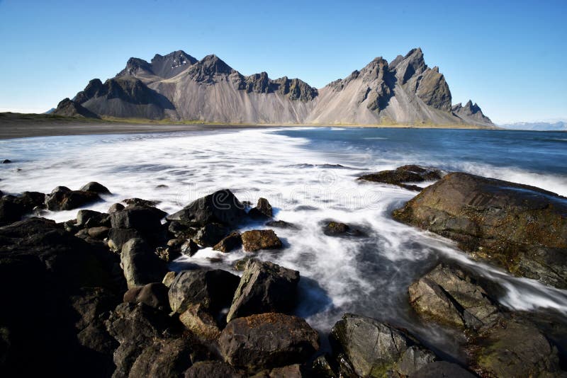 Hermosa vista de las montañas de Vestrahorn con la arena negra y el océano en frente cerca de Hoefn en Islandia imagen de archivo libre de regalías Hermosa vista de las montañas de Vestrahorn con la arena negra y el océano en frente cerca de Hoefn en Islandia imagen de archivo libre de regalías