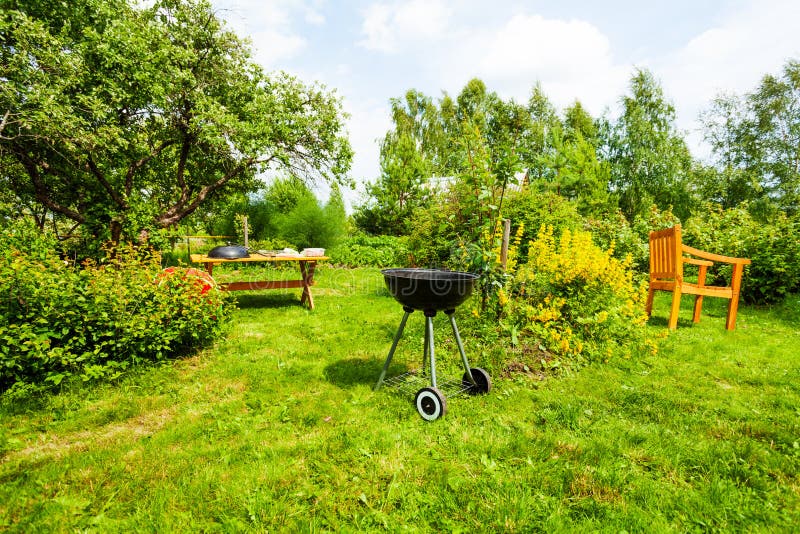 Hermosa vista en jardín con la parrilla, tabla, silla fotografía de archivo Hermosa vista en jardín con la parrilla, tabla, silla fotografía de archivo