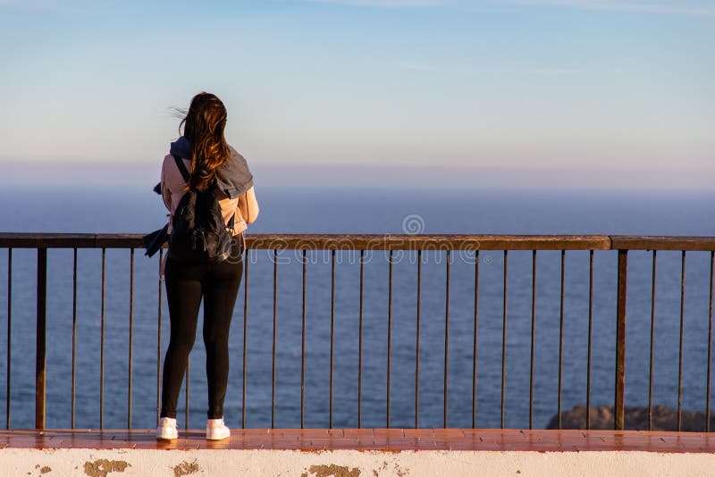 Hermosas mujeres paradas en un mirador en un acantilado durante la puesta de sol imagenes de archivo