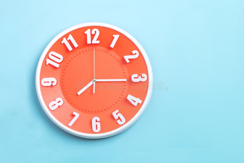 Hermoso reloj de pared naranja sobre fondo azul, concepto de Empieza a trabajar la mañana foto de archivo Hermoso reloj de pared naranja sobre fondo azul, concepto de Empieza a trabajar la mañana foto de archivo