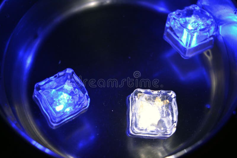 Hermosos y luminosos cubos de hielo azul brillante flotando en una copa de champán con una copa. foto de archivo libre de regalías