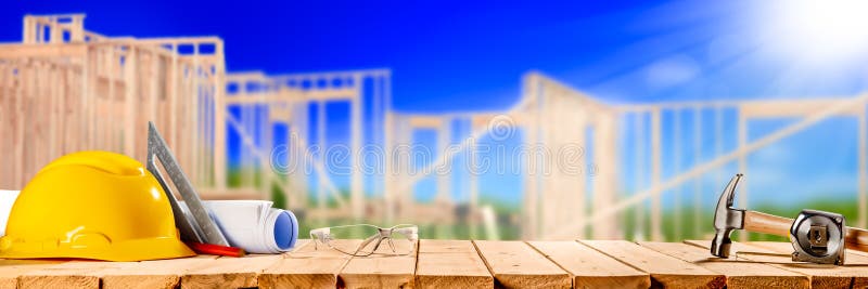 Construction Tools On Wooden Table With New House Framework In Background - Housing Industry Concept. Construction Tools On Wooden Table With New House Framework In Background - Housing Industry Concept