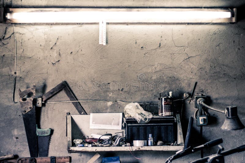 Herramientas viejas del trabajo, estante en una pared sobre un banco de trabajo viejo del vintage en un garaje casero fotos de archivo Herramientas viejas del trabajo, estante en una pared sobre un banco de trabajo viejo del vintage en un garaje casero fotos de archivo