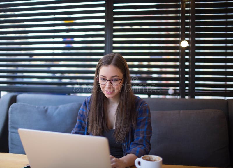 Herrliche Frau, die einen Unternehmensplan für Kaffeestube auf Laptop-Computer schreibt stockfoto