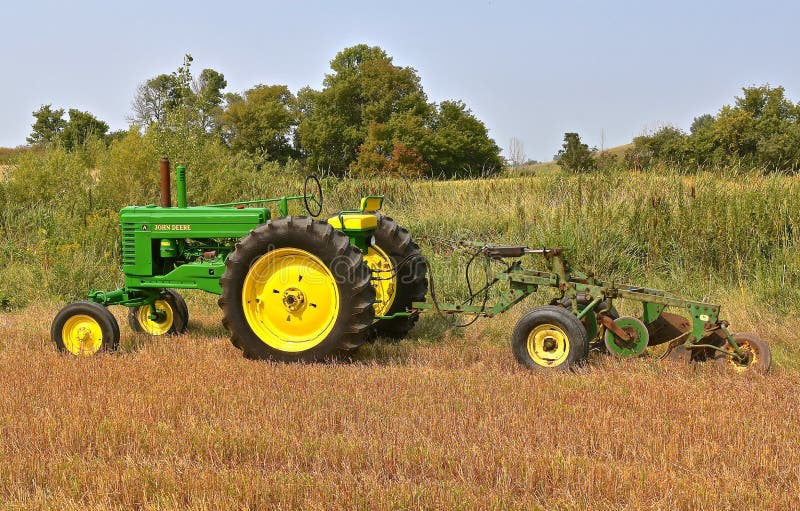 Herstelde die John Deere-tractortractor aan een ploeg van de vier bodemreis wordt vastgehaakt royalty-vrije stock fotografie Herstelde die John Deere-tractortractor aan een ploeg van de vier bodemreis wordt vastgehaakt royalty-vrije stock fotografie