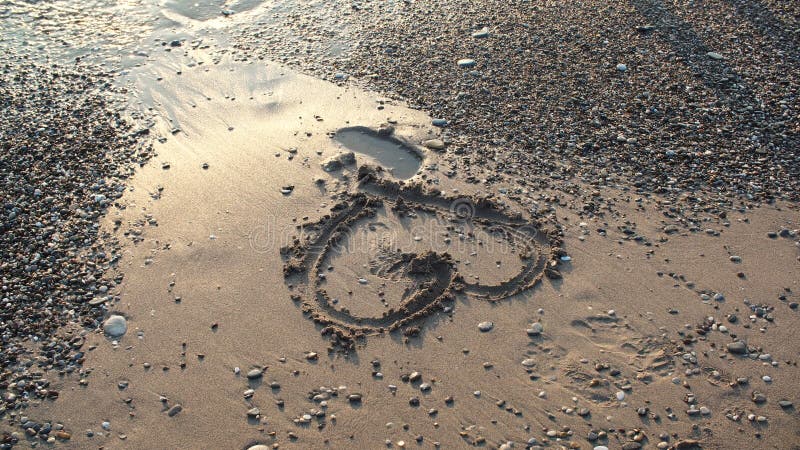 Herz im Sand auf dem Seeufer am sonnigen Tag