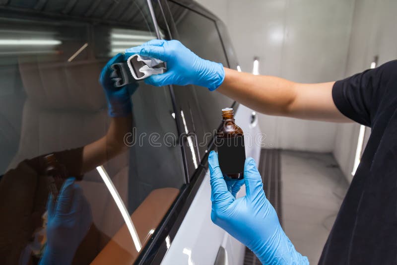 Het aanbrengen van een nano-keramische laag voor hydrofobe effecten op de ramen van de auto door een mannelijke werknemer met een