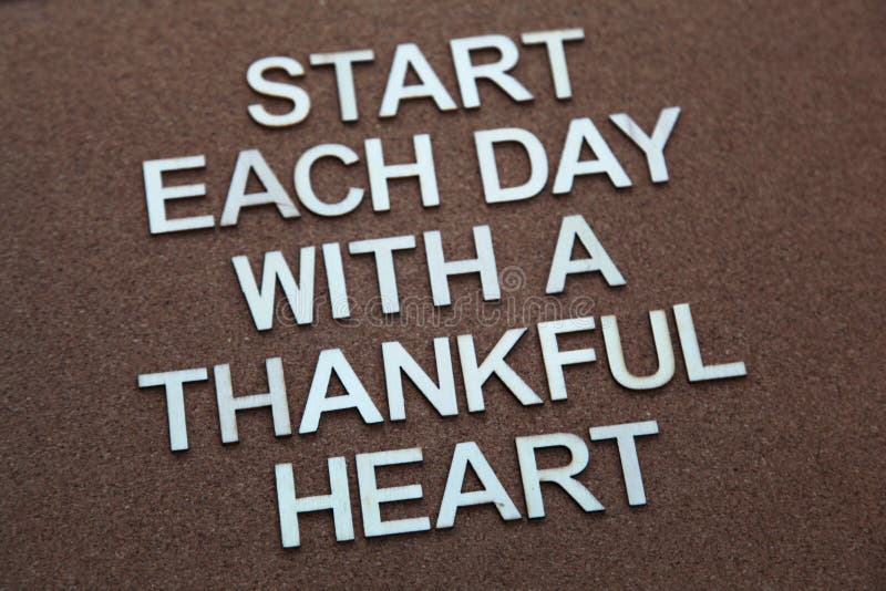 Encouraging words that says to start each day with a thankful heart on a corkboard background in brown. Encouraging words that says to start each day with a thankful heart on a corkboard background in brown