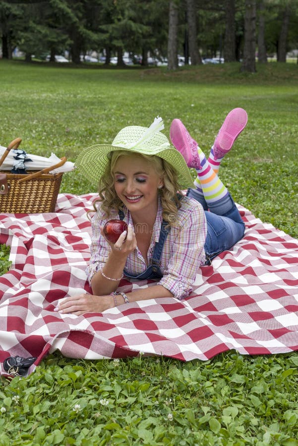 Het aantrekkelijke jonge blonde vrouw stellen in openlucht tijdens picknick royalty-vrije stock foto Het aantrekkelijke jonge blonde vrouw stellen in openlucht tijdens picknick royalty-vrije stock foto