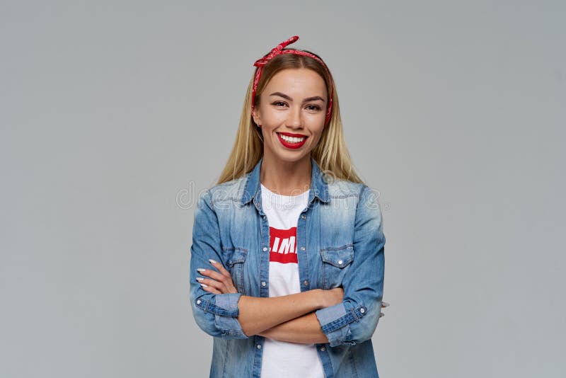 Het aantrekkelijke jonge vrouw glimlachen ruim vouwde haar handen op haar het denimoverhemd en t-shirt van de borst vrijetijdskle stock fotografie Het aantrekkelijke jonge vrouw glimlachen ruim vouwde haar handen op haar het denimoverhemd en t-shirt van de borst vrijetijdskle stock fotografie
