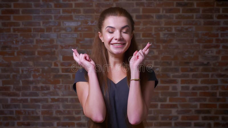 Het artistieke Kaukasische gemberwijfje wenst geluk met twee gekruiste vingers dit, makend komen haar dromen waar, terwijl