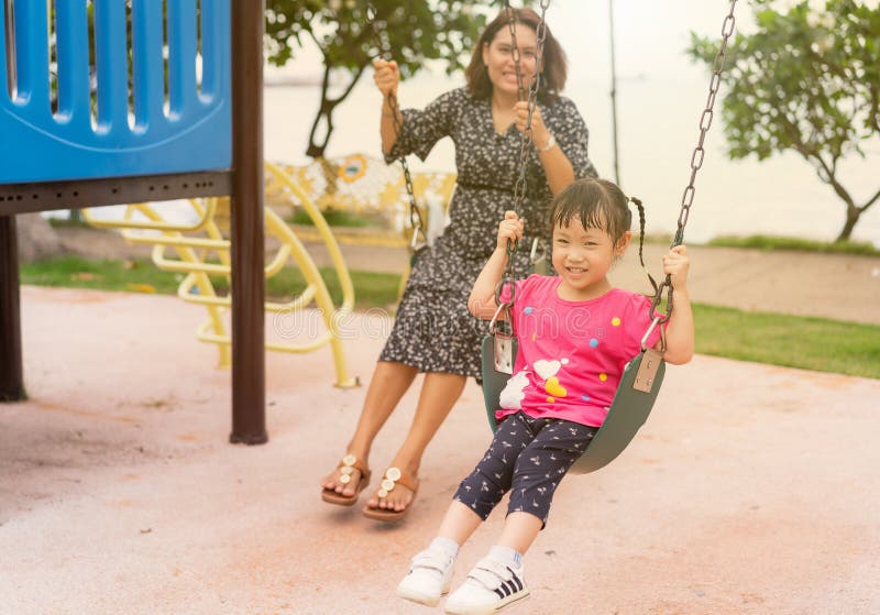 Het Aziatische jonge moederspel op een schommeling met haar aanbiddelijke kleine dochter bij het park, het mamma en weinig hebben royalty-vrije stock afbeeldingen Het Aziatische jonge moederspel op een schommeling met haar aanbiddelijke kleine dochter bij het park, het mamma en weinig hebben royalty-vrije stock afbeeldingen