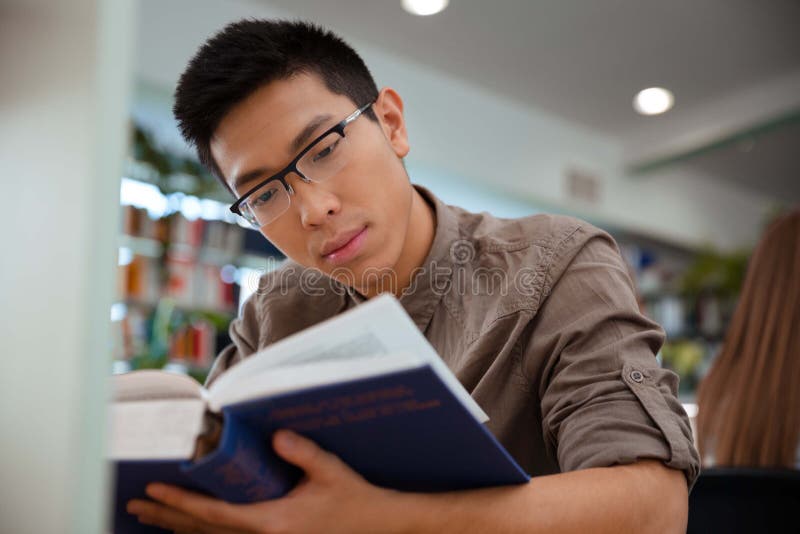 Het Aziatische mannelijke boek van de studentenlezing op universiteit royalty-vrije stock foto Het Aziatische mannelijke boek van de studentenlezing op universiteit royalty-vrije stock foto