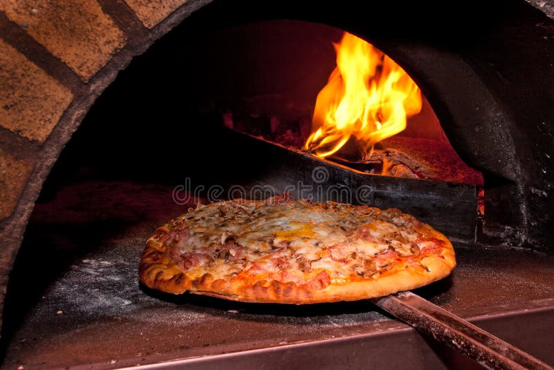 Het baksel van de pizza in de oven royalty-vrije stock afbeelding Het baksel van de pizza in de oven royalty-vrije stock afbeelding