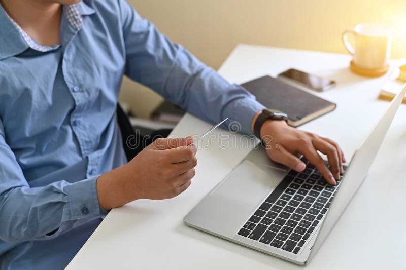 Het bebouwde schot van de mens voerde creditcardinformatie in terwijl online het winkelen stock fotografie Het bebouwde schot van de mens voerde creditcardinformatie in terwijl online het winkelen stock fotografie
