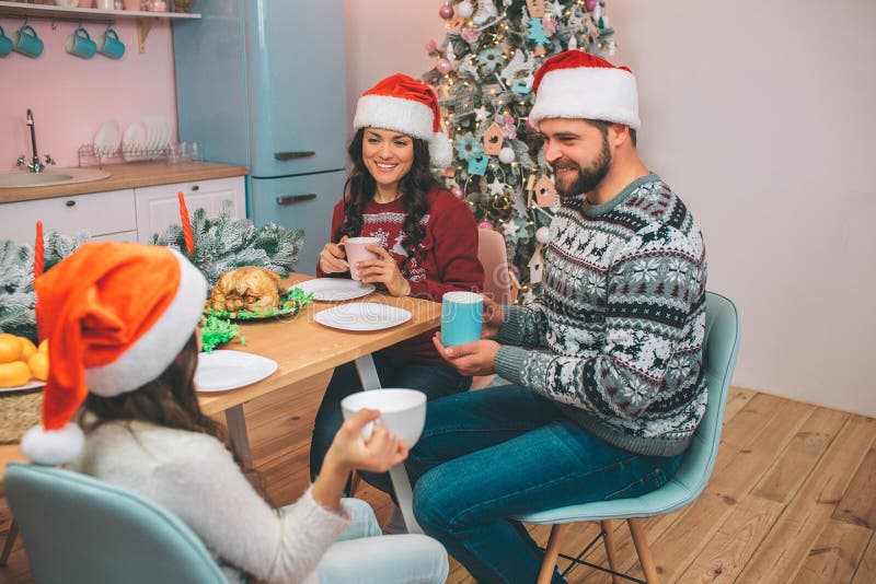 Het beeld van mooie familiezitting bij tabel en bekijkt elkaar Zij houden koppen in handen De mensen glimlachen aan elkaar stock fotografie Het beeld van mooie familiezitting bij tabel en bekijkt elkaar Zij houden koppen in handen De mensen glimlachen aan elkaar stock fotografie