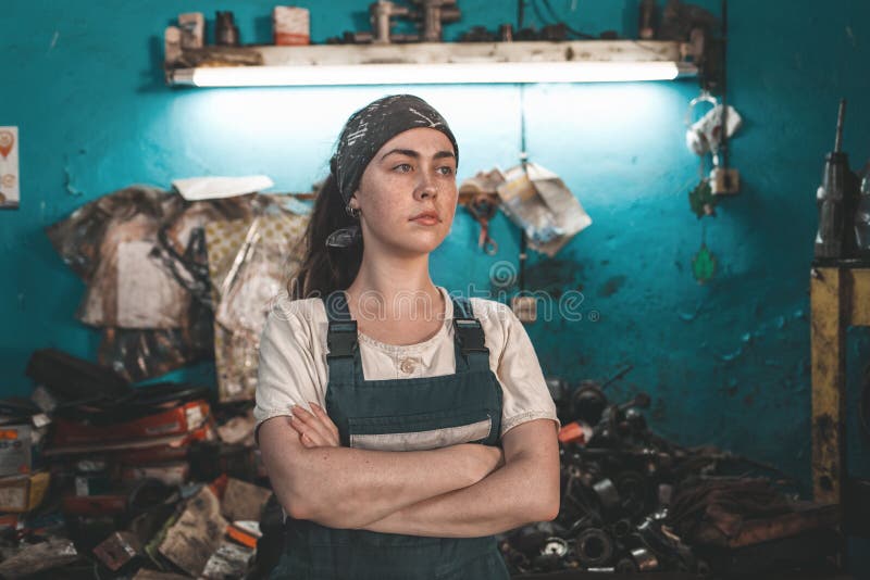 Het begrip kleine onderneming, feminisme en gelijkheid van vrouwen Een jonge vrouw in werkkleding die zich voor een auto-reparati