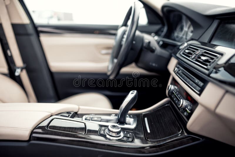 Het beige en zwarte binnenland van moderne auto, close-updetails van automatisch transmissie en toestel plakt tegen stuurwielbede stock foto Het beige en zwarte binnenland van moderne auto, close-updetails van automatisch transmissie en toestel plakt tegen stuurwielbede stock foto