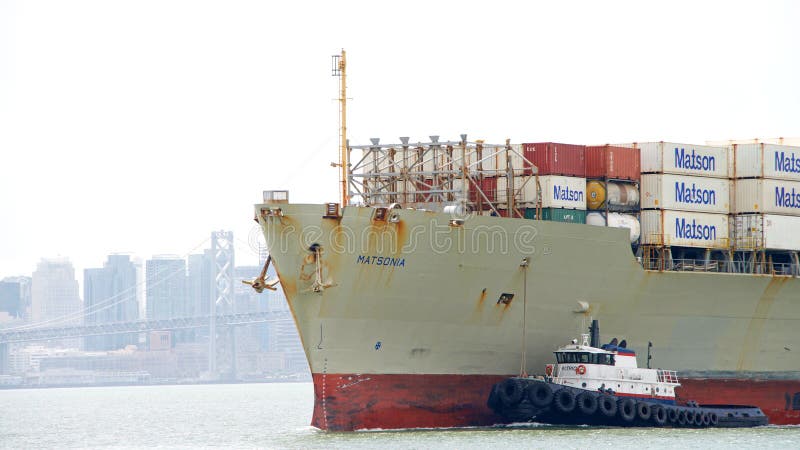Het bijwonende Vrachtschip MATSONIA van de sleepbootpatriot aan manoeuvre royalty-vrije stock afbeelding Het bijwonende Vrachtschip MATSONIA van de sleepbootpatriot aan manoeuvre royalty-vrije stock afbeelding