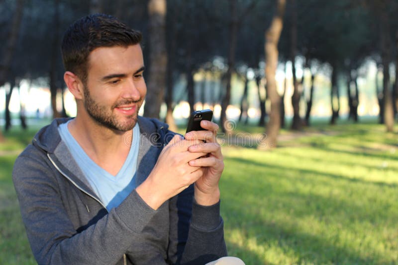 Het blije mannelijke texting in het park royalty-vrije stock afbeeldingen Het blije mannelijke texting in het park royalty-vrije stock afbeeldingen