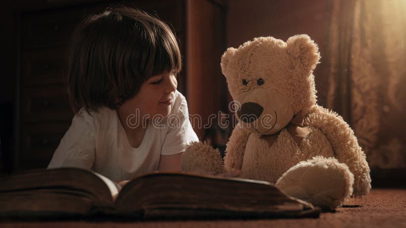 Het boek van de jongenslezing met zijn teddybeer royalty-vrije stock afbeelding Het boek van de jongenslezing met zijn teddybeer royalty-vrije stock afbeelding