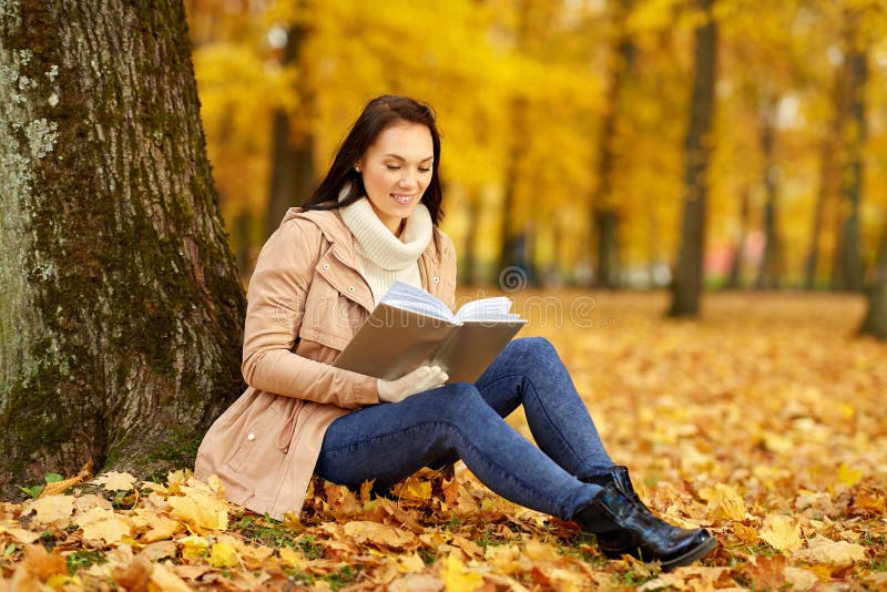 Het boek van de vrouwenlezing bij de herfstpark stock foto's Het boek van de vrouwenlezing bij de herfstpark stock foto's