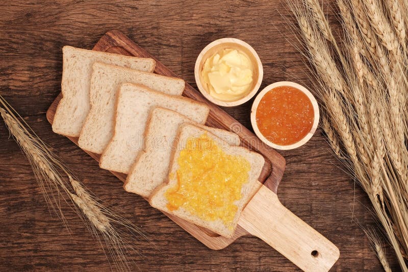 Het brood van de plak gehele tarwe, boter en oranje jam stock afbeelding Het brood van de plak gehele tarwe, boter en oranje jam stock afbeelding