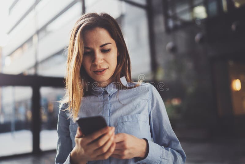 Het charmante jonge bedrijfsvrouw spreken met partner via mobiele telefoon terwijl status op modern commercieel centrum stock foto's Het charmante jonge bedrijfsvrouw spreken met partner via mobiele telefoon terwijl status op modern commercieel centrum stock foto's