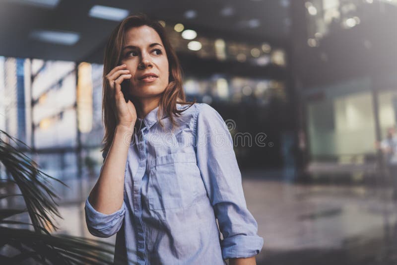Het charmante jonge bedrijfsvrouw spreken met partner via mobiele telefoon terwijl status op modern commercieel centrum royalty-vrije stock afbeelding Het charmante jonge bedrijfsvrouw spreken met partner via mobiele telefoon terwijl status op modern commercieel centrum royalty-vrije stock afbeelding