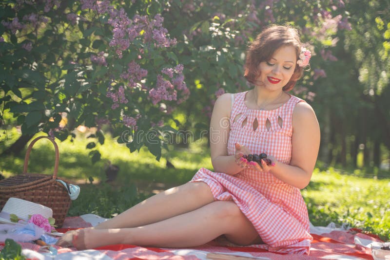 Het charmante pinup meisje geniet van een rust en van een picknick op het groene de zomergras de vrij uitstekende stijl Kaukasisc stock foto's Het charmante pinup meisje geniet van een rust en van een picknick op het groene de zomergras de vrij uitstekende stijl Kaukasisc stock foto's