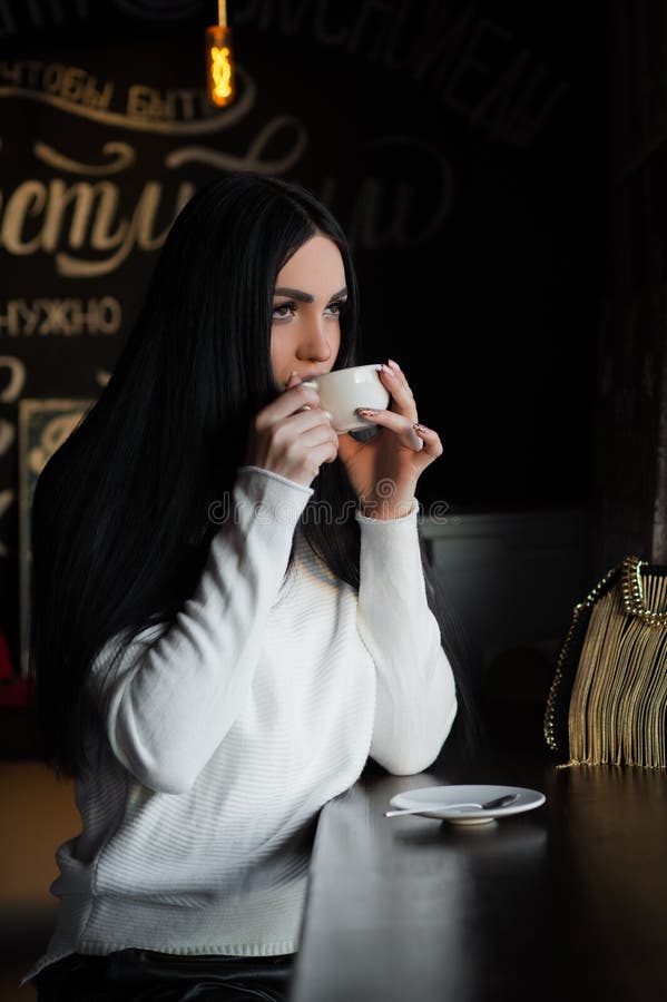 Het charmeren brunette in koffie het drinken koffie royalty-vrije stock afbeelding Het charmeren brunette in koffie het drinken koffie royalty-vrije stock afbeelding