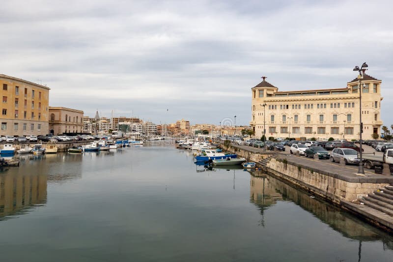 SIRACUSA, SICILY - FEBRUARY 13, 2020: The cityscape of Siracusa city, Sicily, Italy with Ortea Palace Luxury Hotel on bank of the water canal. SIRACUSA, SICILY - FEBRUARY 13, 2020: The cityscape of Siracusa city, Sicily, Italy with Ortea Palace Luxury Hotel on bank of the water canal