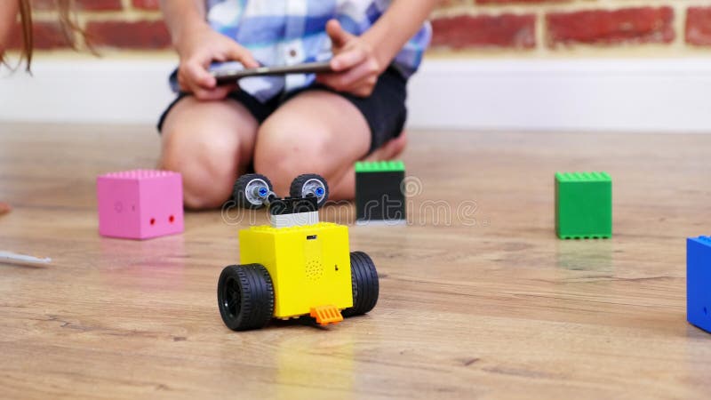 Het close-up, radio-gecontroleerde robotbewegingen op vloer, kleine genieën, kinderen speelt elektronische robots, auto's, modern