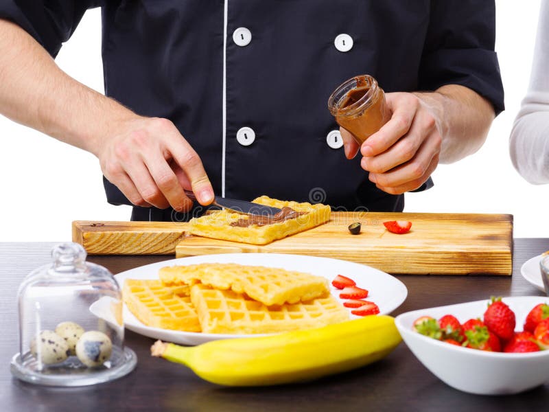 Het close-up van de vlek van chef-kok` s handen met een mes kookte condens op wafels stock afbeeldingen Het close-up van de vlek van chef-kok` s handen met een mes kookte condens op wafels stock afbeeldingen