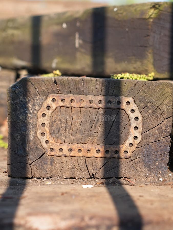 Het close-up van een oud blok van hout met een stuk van ijzer met gaten maakte op de oppervlakte vast stock afbeeldingen Het close-up van een oud blok van hout met een stuk van ijzer met gaten maakte op de oppervlakte vast stock afbeeldingen