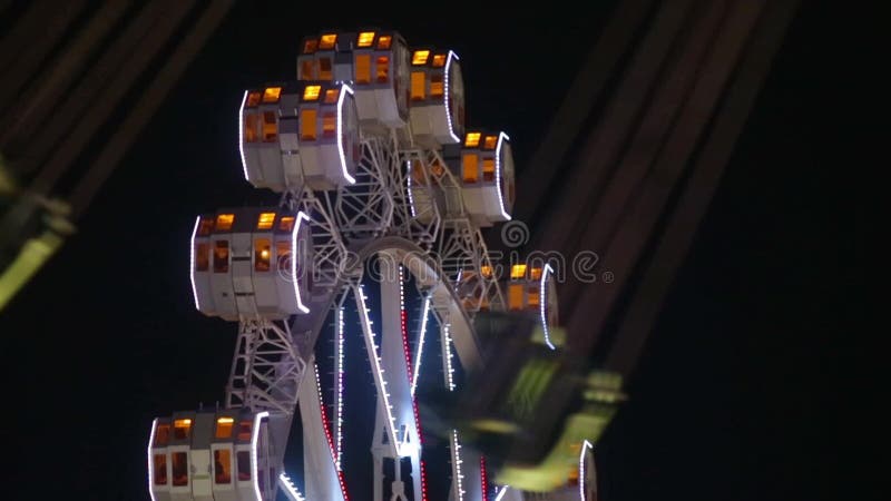 Het close-up van Reuzenrad en unfocused carrousel door te roteren bij nacht