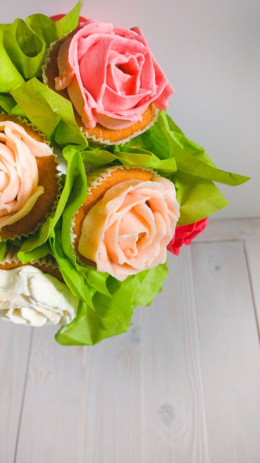Het close-upbeeld van boeket in rode pot maakte van cupcakes tegen witte houten achtergrond Mooi schot van snoepjes en stock foto's Het close-upbeeld van boeket in rode pot maakte van cupcakes tegen witte houten achtergrond Mooi schot van snoepjes en stock foto's